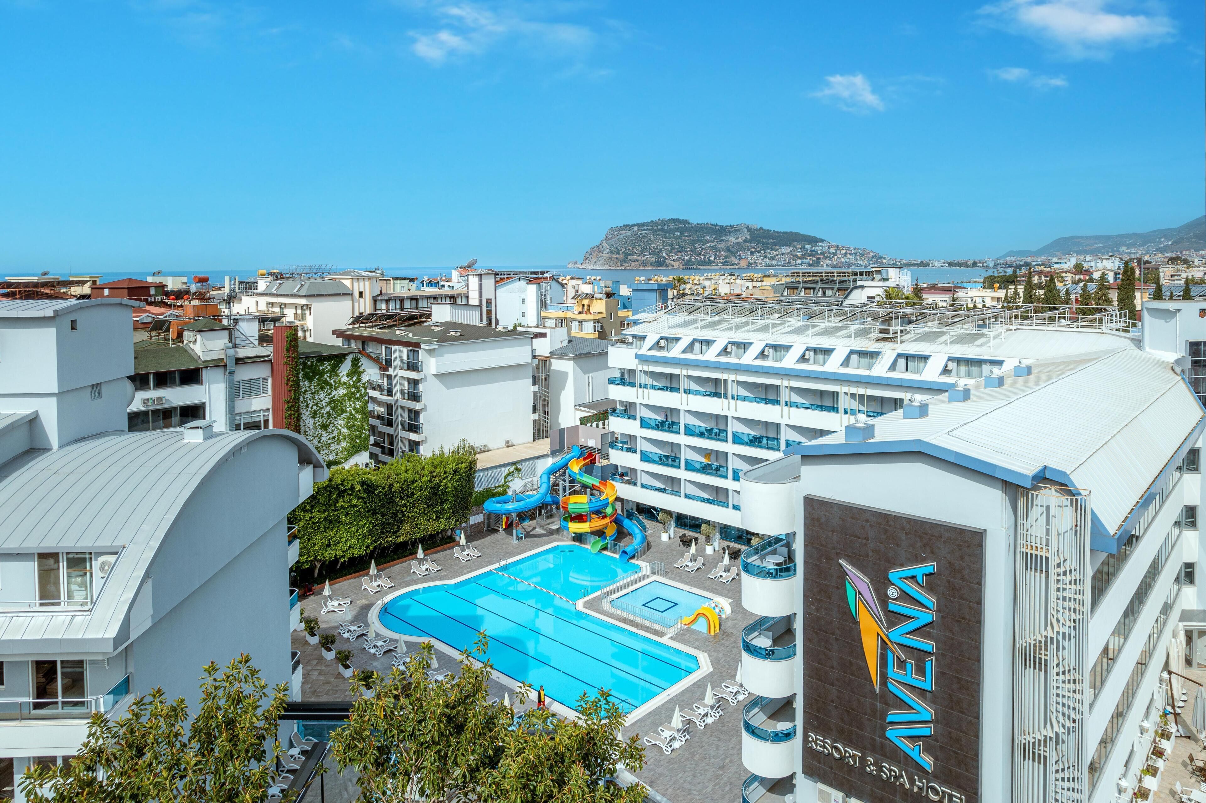 A resort with a swimming pool, a water slide, and a view of the sea.