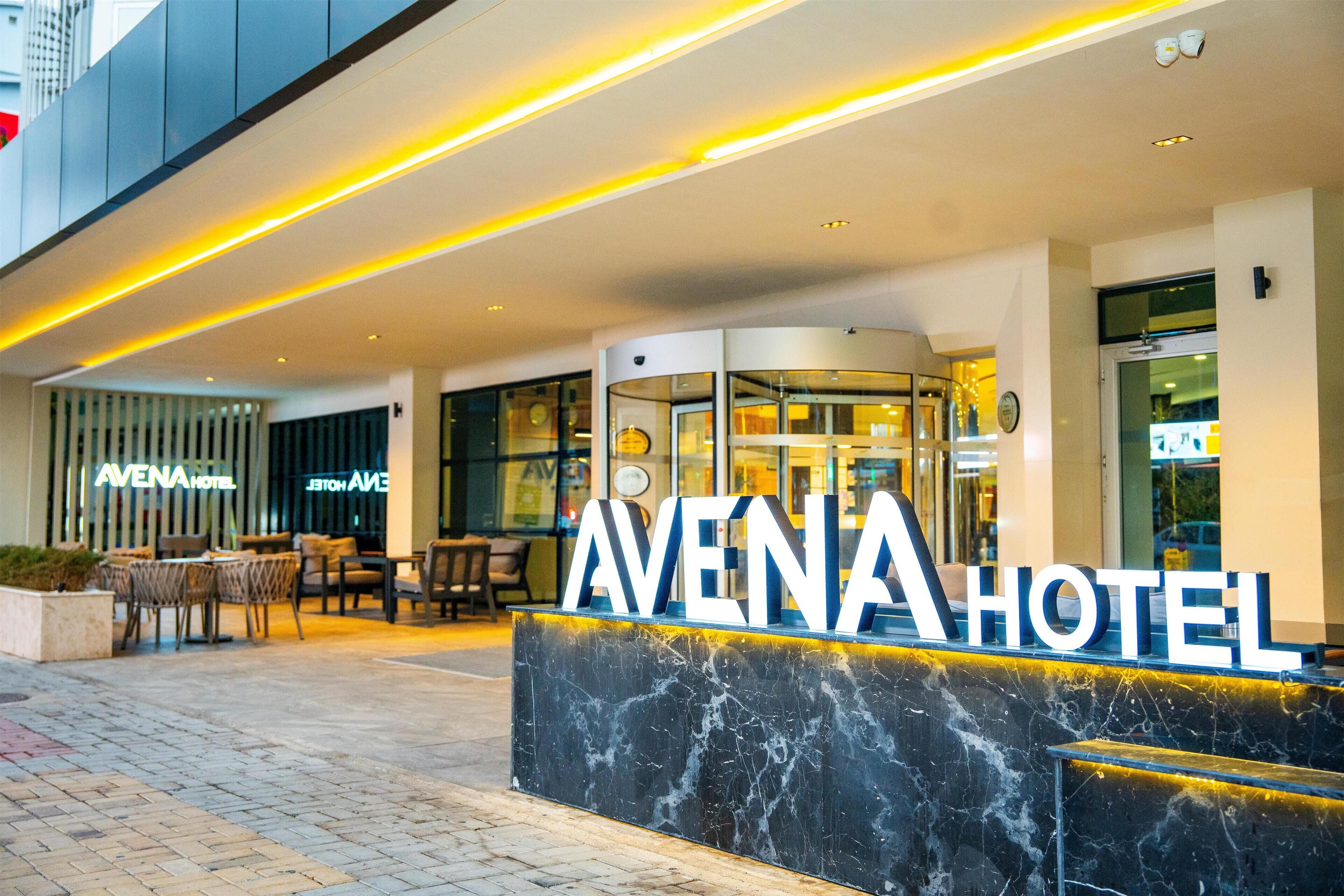 The exterior of the Avena Hotel with a marble reception desk and outdoor seating area.