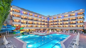 A hotel with a large indoor swimming pool, multiple balconies, and a children's water park. - Avena Resort & Spa Hotel - All Inclusive  (Alanya)