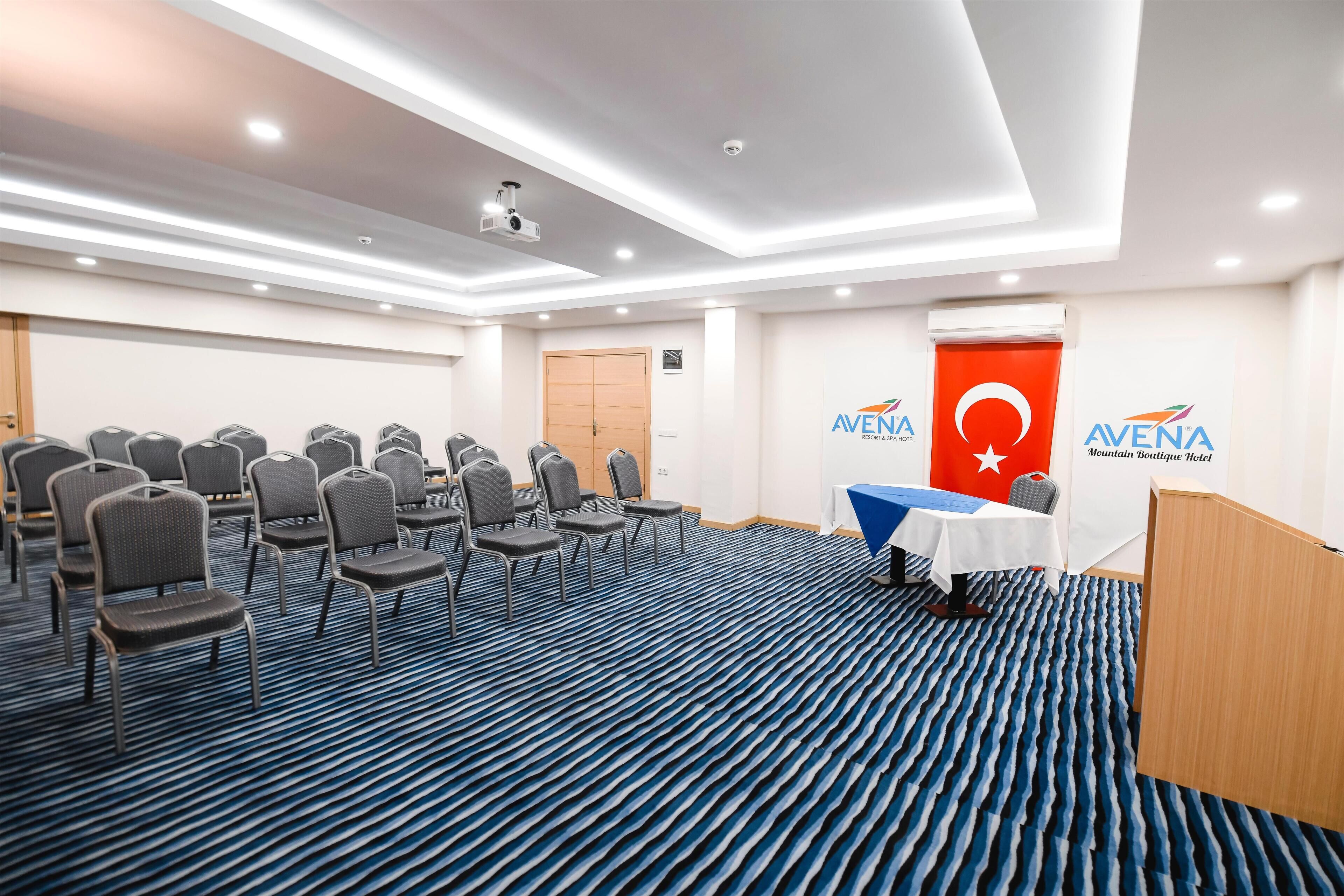 A conference room with rows of chairs, a podium, and a table with a flag.