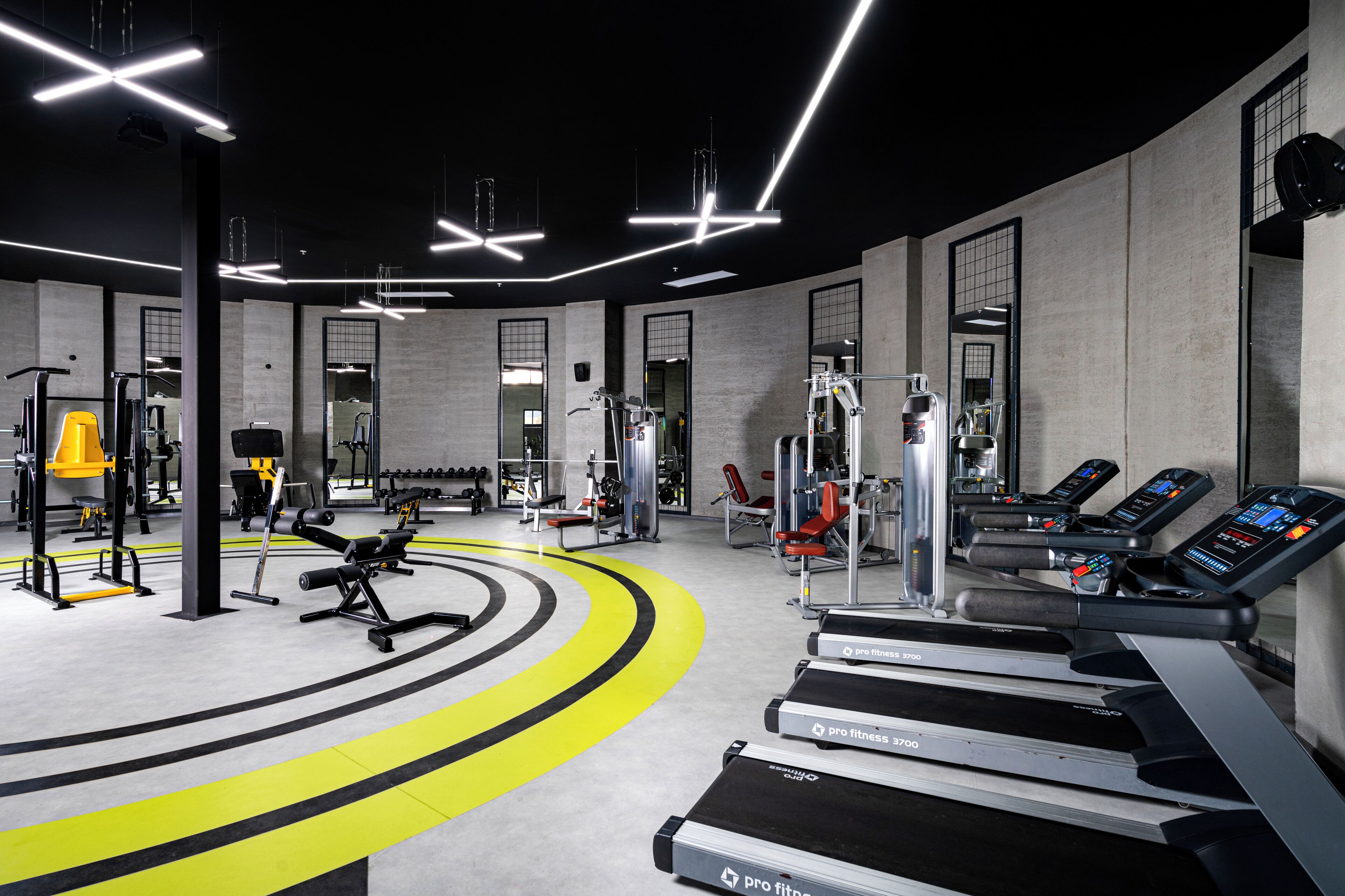 A gym with treadmills, weight machines, and a mirror wall.