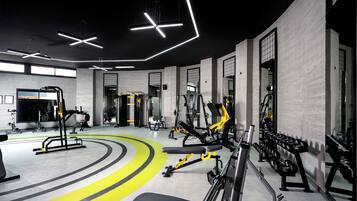 Un gimnasio moderno con diverso equipo de ejercicio, un banco central y una pista de atletismo amarilla.