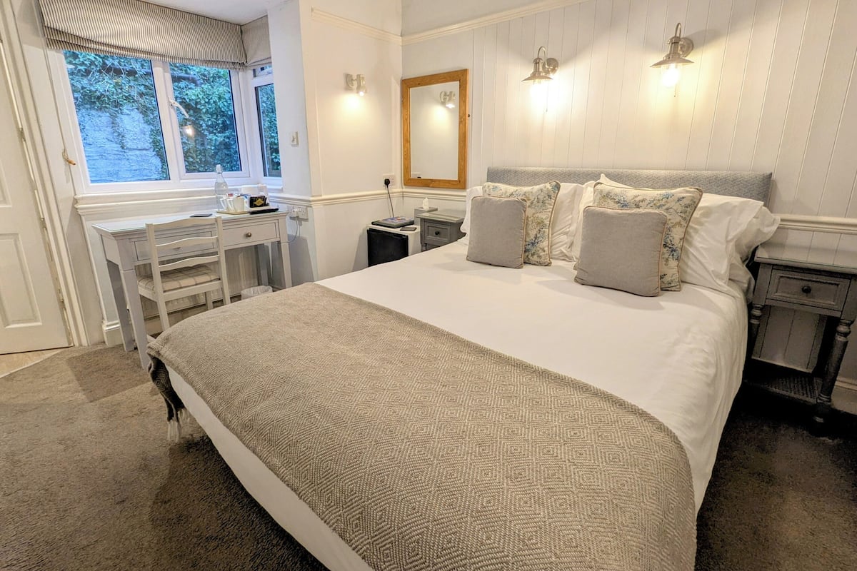 Ein Schlafzimmer mit einem großen Bett, einem Schreibtisch und einem Fenster.