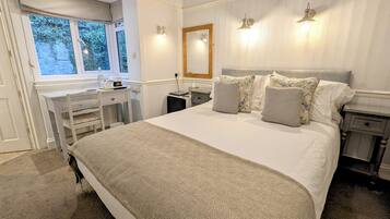 A bedroom with a large bed, a desk, and a window.