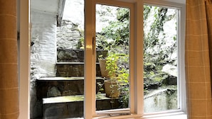 Una ventana con vistas a escalones de piedra y plantas en macetas.