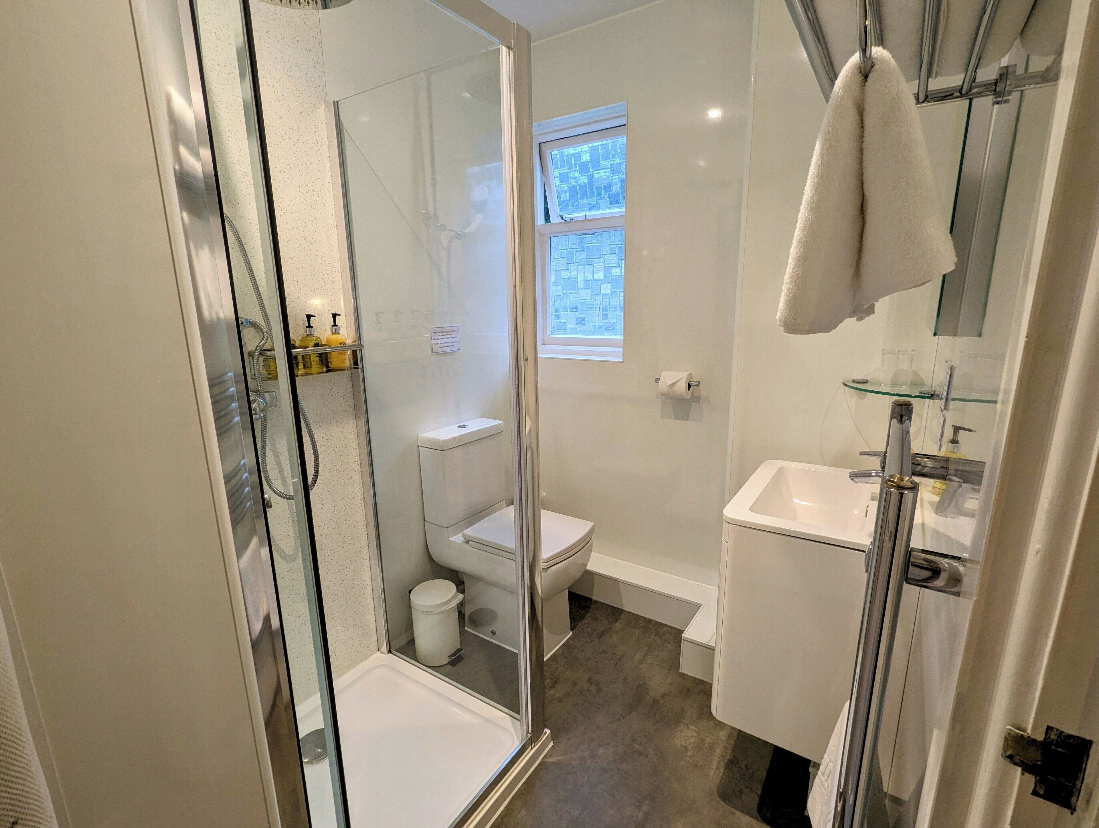 A modern bathroom with a glass-enclosed shower, a toilet, and a sink.