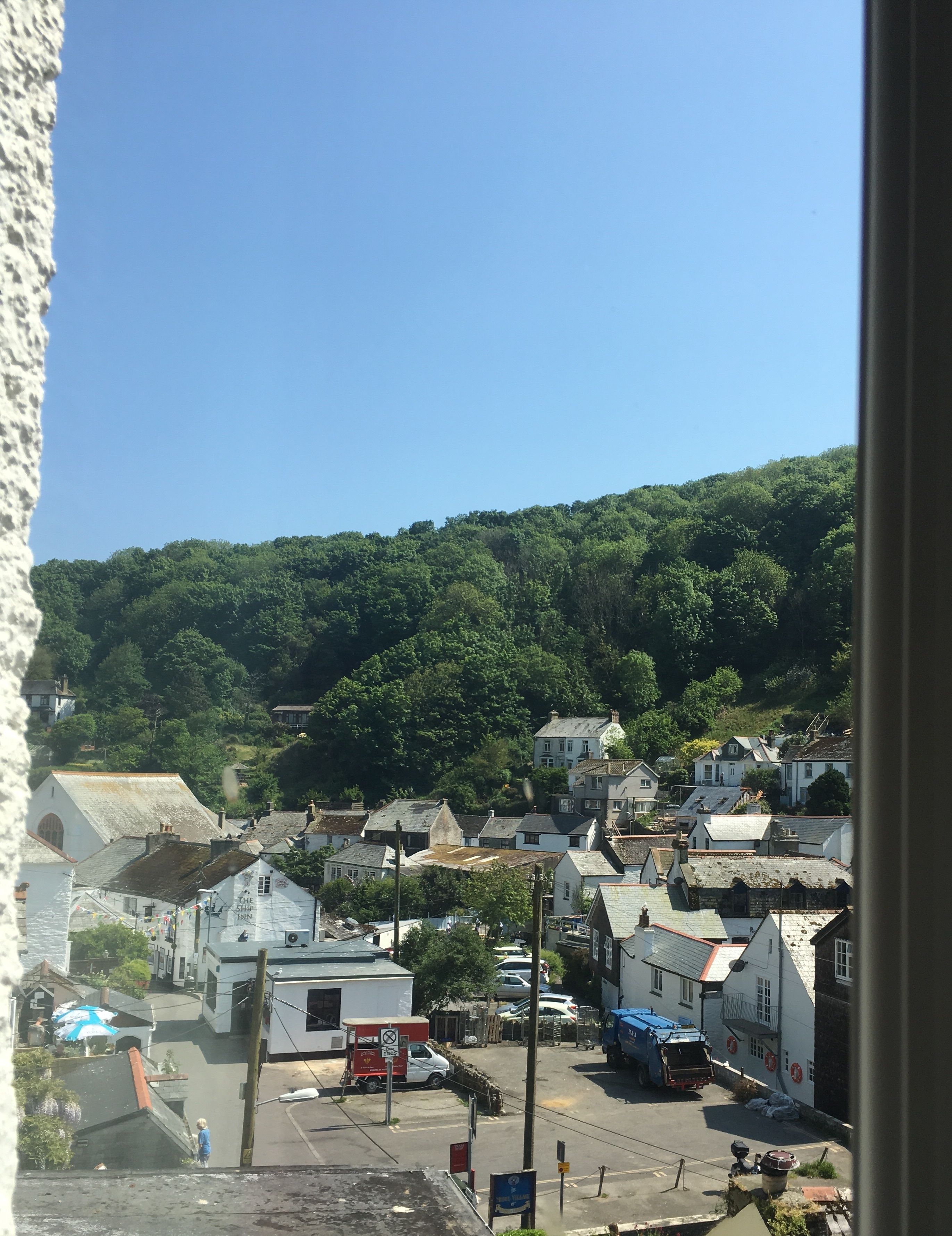 A town with buildings on a hillside, a clear sky, and a person walking.