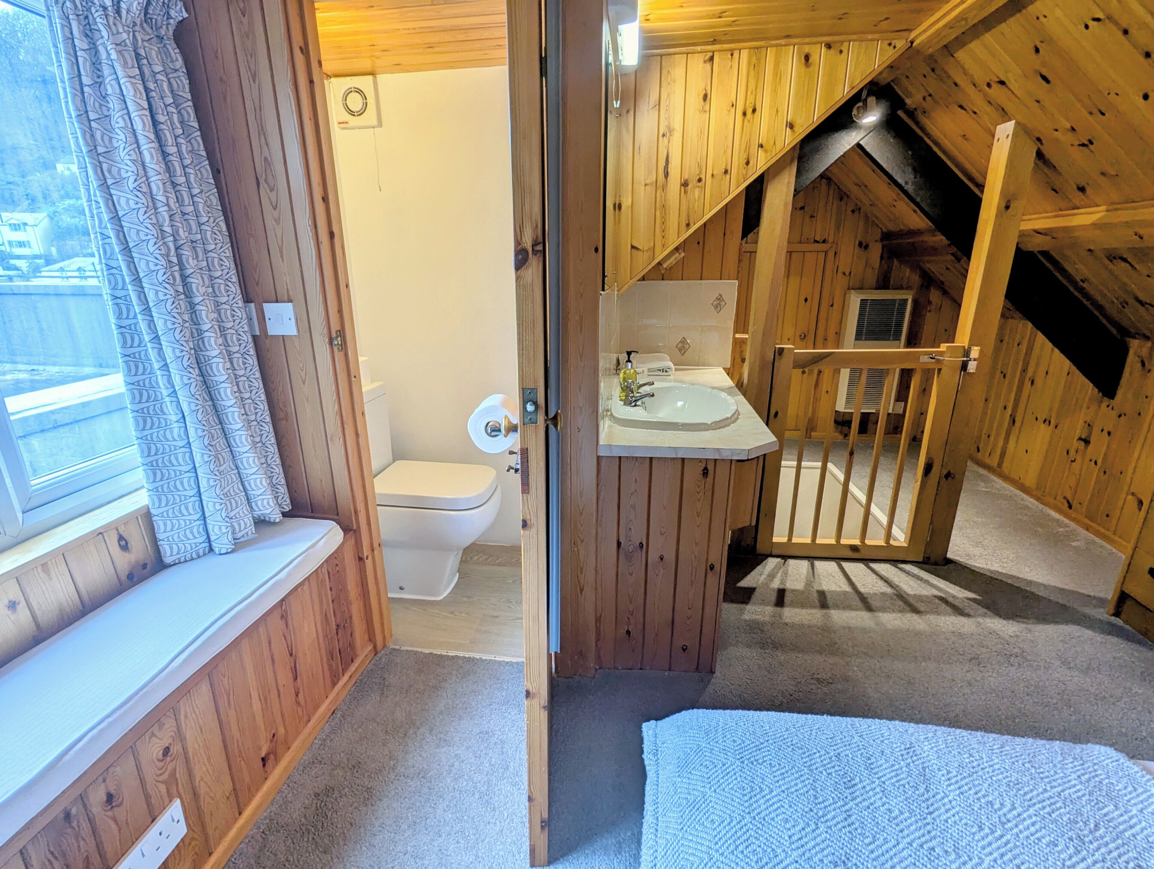 A wooden cabin with a bathroom featuring a toilet, sink, and shower.