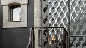 Fachada de edifício com design de janela geométrica e portão de metal.