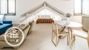 Quarto moderno estilo loft com teto inclinado, um sofá acolhedor, uma mesa de jantar e vista para a cidade.