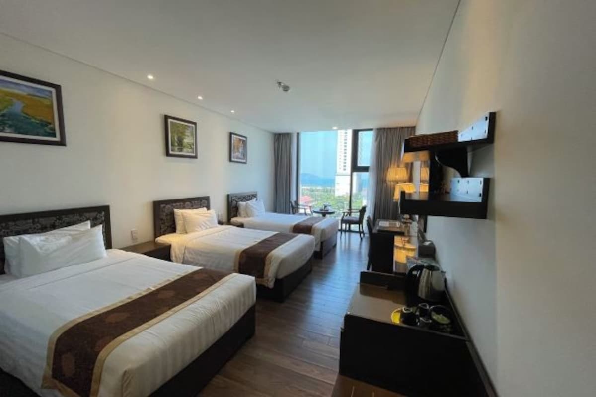 Habitación de hotel con dos camas, un escritorio, una silla, un televisor y una ventana con vistas.