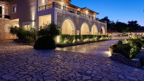 A modern villa with a stone facade, arched windows, and a spacious courtyard.