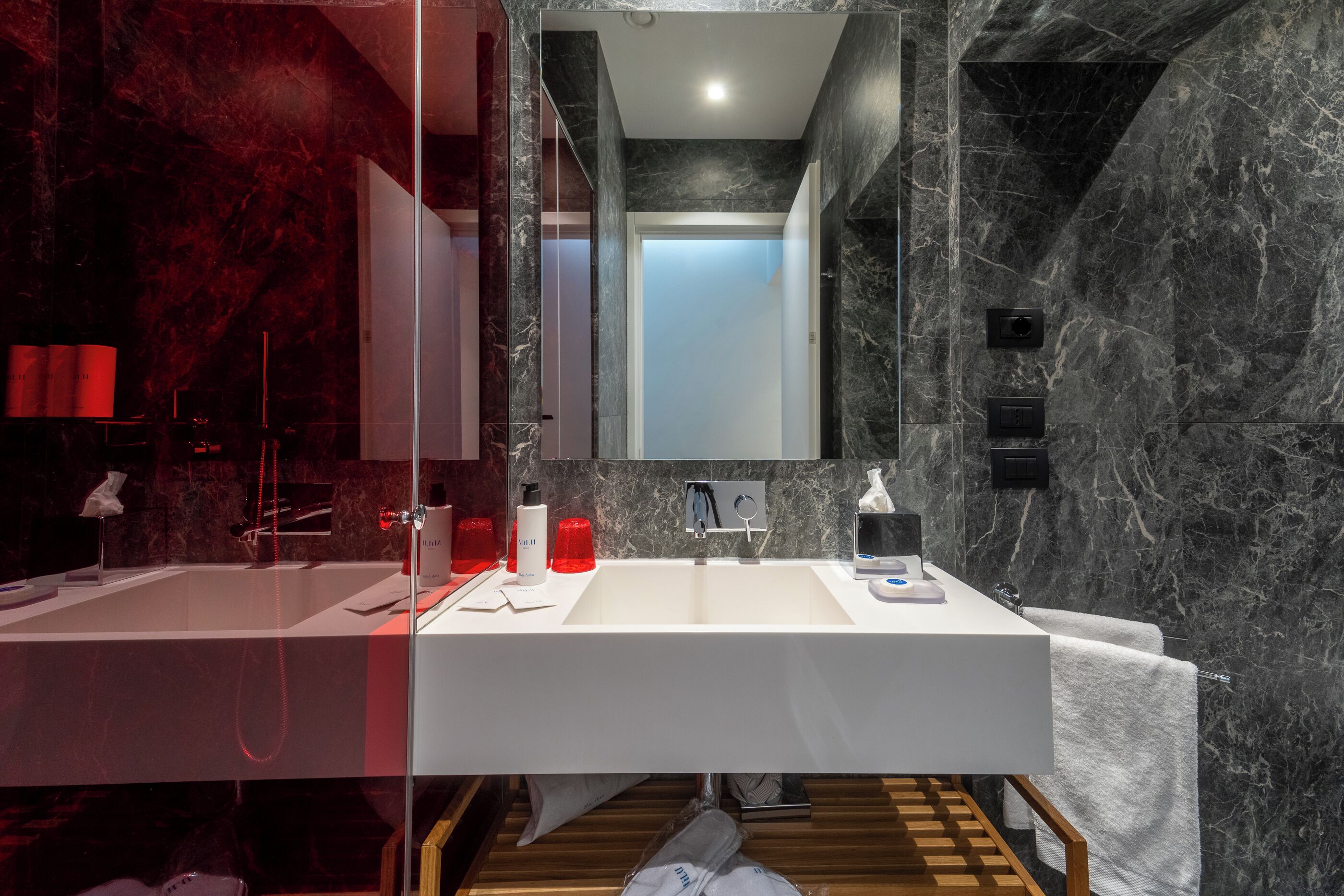 A modern bathroom with a double sink, a large mirror, and marble walls.