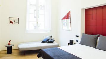 A bedroom with a bed, a bench, a small table, and a window.