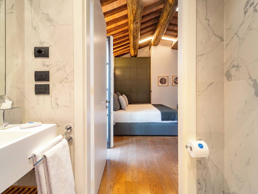 Une salle de bain moderne avec un lavabo blanc, un porte-serviettes et des murs en marbre.