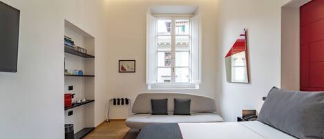 Un dormitorio moderno con cama, sofá, ventana y estantería.
