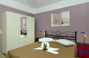 A bedroom with a bed, a wardrobe, a nightstand, and a wall-mounted lamp.