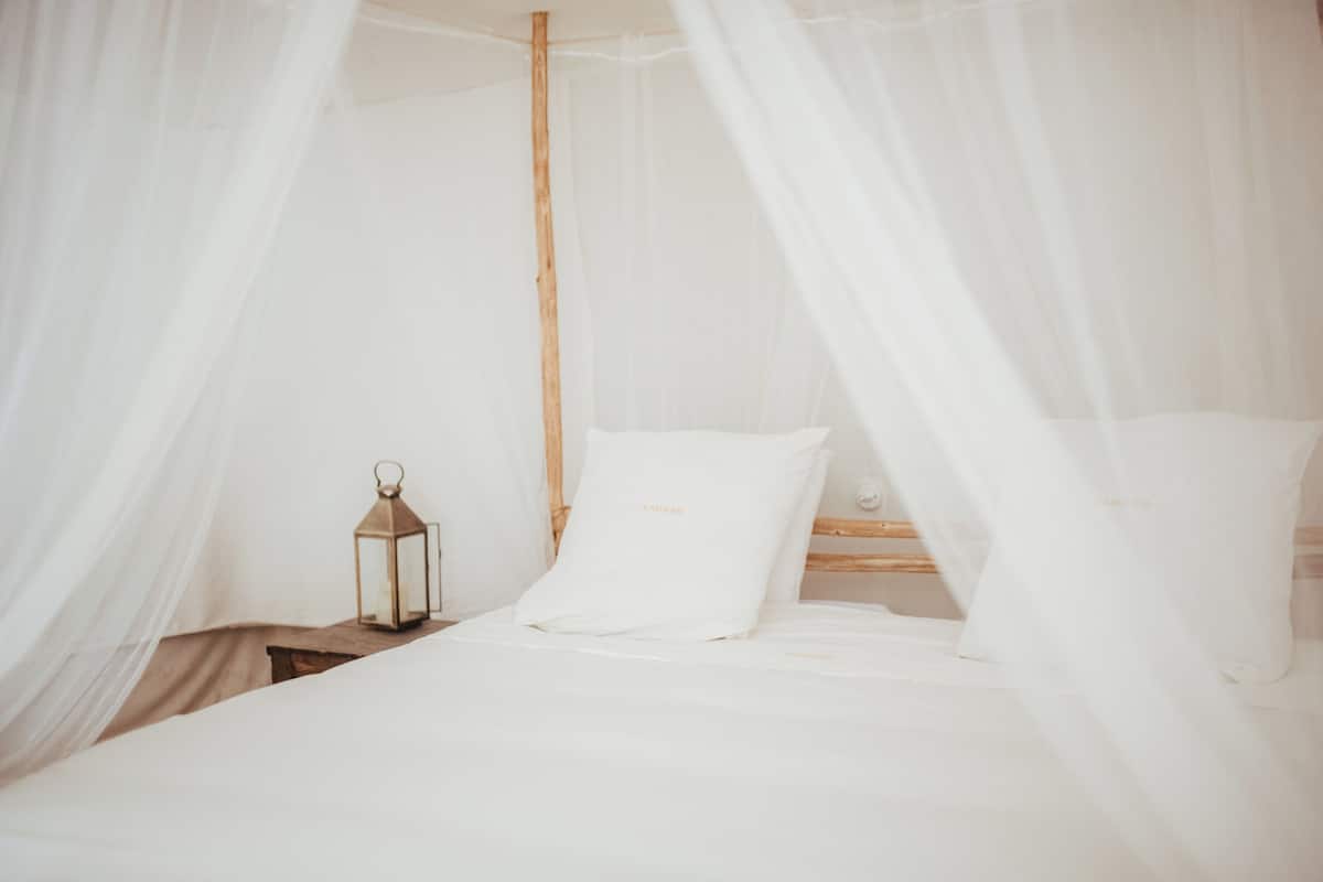 A bed with white bedding, a wooden headboard, and a lantern on a nightstand.