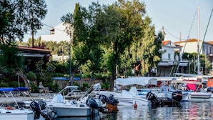 A marina with several boats docked, surrounded by trees and buildings. - Limani Cottage (Alonissos)