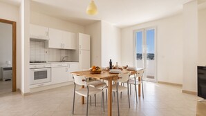 Una cucina moderna con mobili bianchi, un tavolo da pranzo in legno e un'ampia finestra.