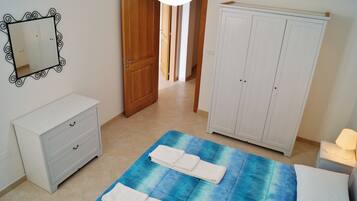 Quarto com cama, mesa de cabeceira, penteadeira, guarda-roupa e espelho.