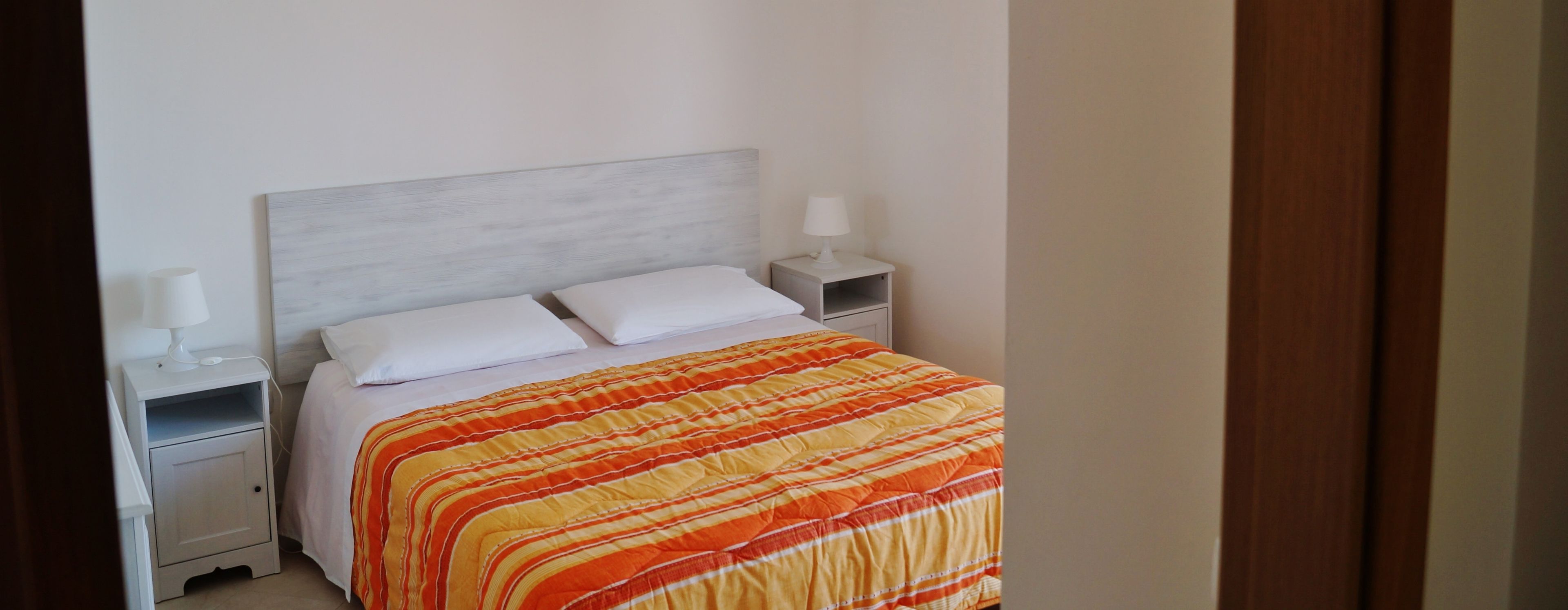 Un dormitorio con una cama, dos mesitas de noche y una mesita auxiliar.