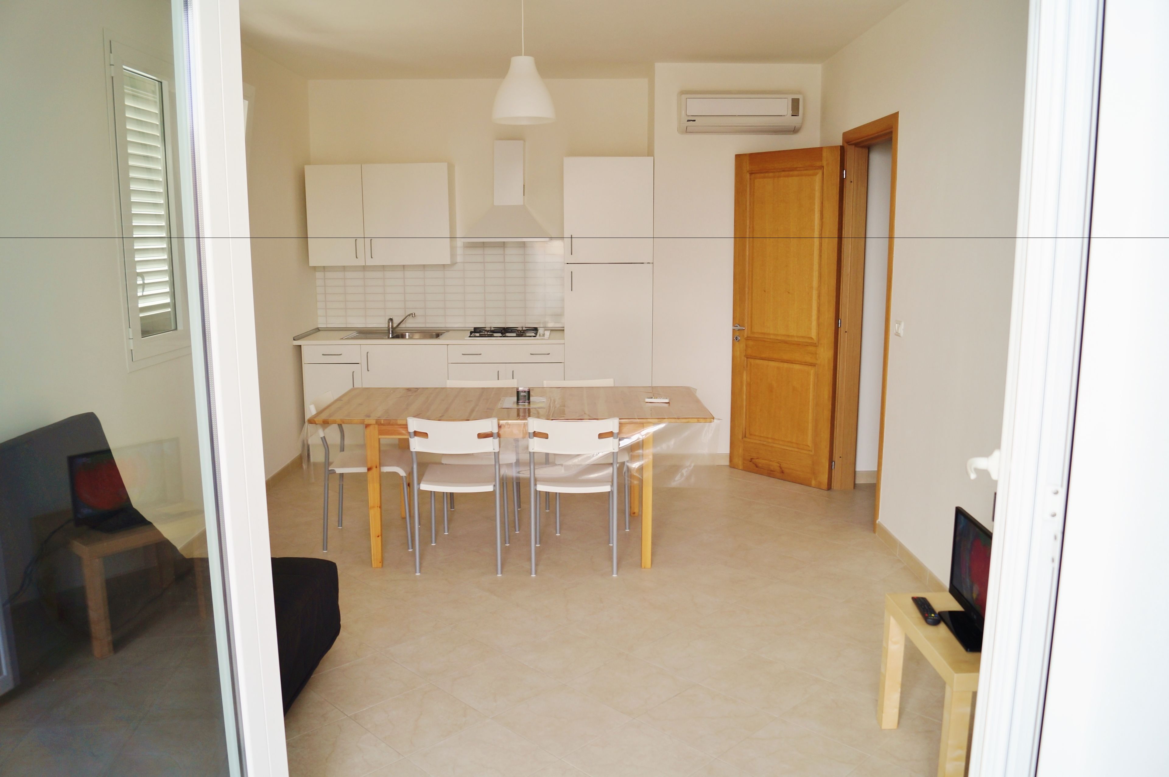 A modern kitchen with white cabinets, a wooden dining table, and chairs.