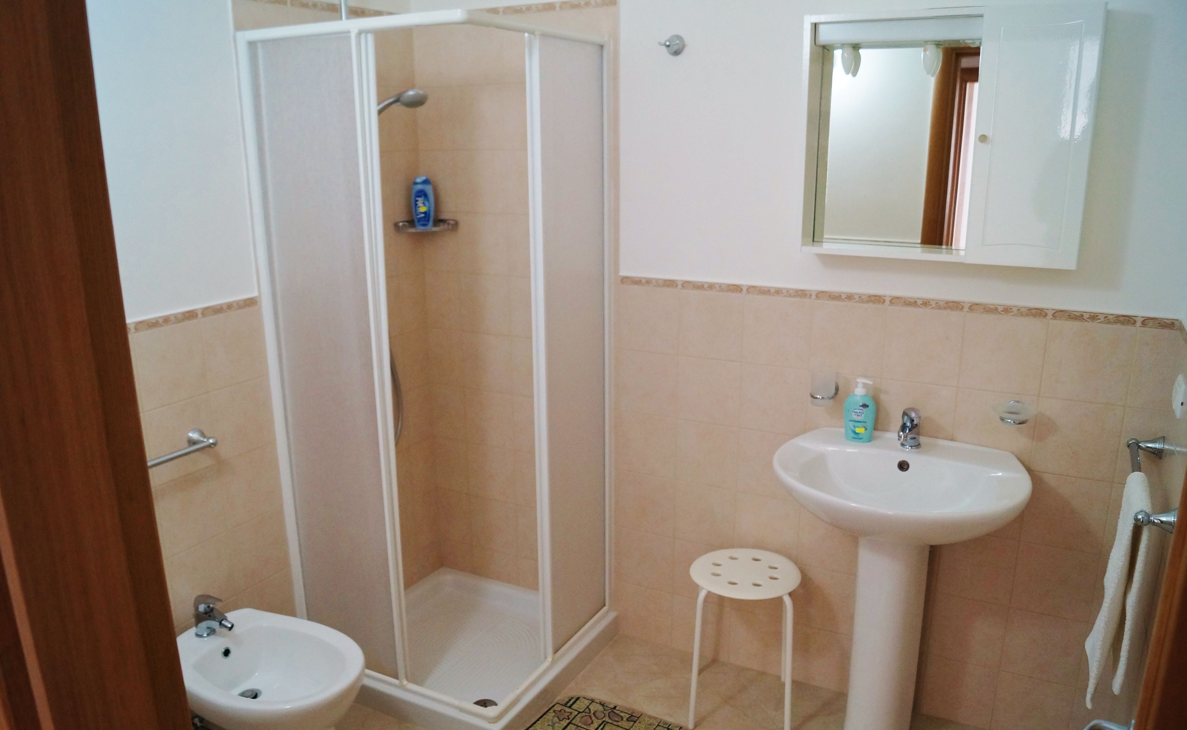 Un baño con ducha, lavamanos y espejo.