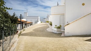 Un sentiero lastricato che conduce a un edificio bianco con tetto in tegole rosse.