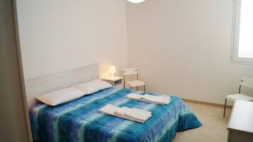 A bedroom with a bed, a nightstand, a chair, and a desk.