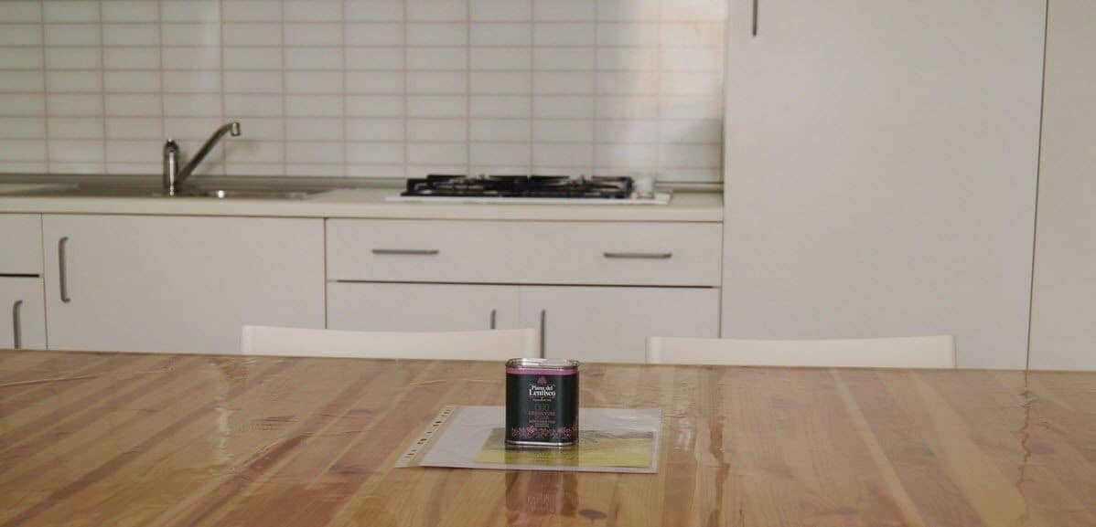 A kitchen with a wooden table, a can of drink, and white cabinets.