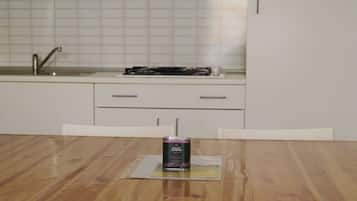 A kitchen with a wooden table, a can of drink, and white cabinets.