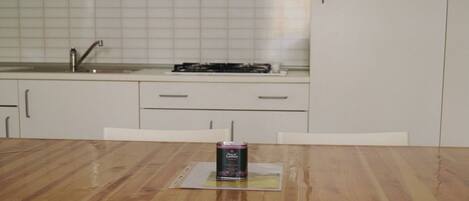 Una cocina con una mesa de madera, una lata de bebida y armarios blancos.