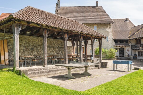 A courtyard with outdoor seating, stone walls, and a traditional tiled roof. - Youth Hostel Brugg (Brugg)