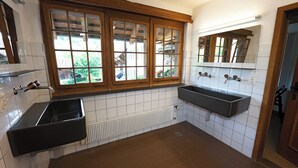 A bathroom with two sinks, a window with wooden frames, a mirror, and a radiator. - Youth Hostel Brugg (Brugg)