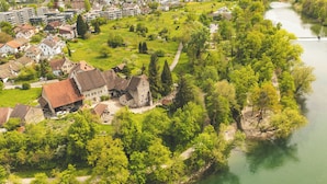 An aerial view of a riverside town with historic buildings, a park, and a bridge. - Youth Hostel Brugg (Brugg)