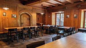 A wooden interior with multiple tables and chairs, a large arched doorway, and framed pictures on the walls. - Youth Hostel Brugg (Brugg)