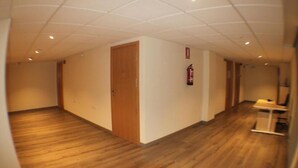 A hallway with wooden flooring, a wooden door, and a fire extinguisher on the wall. - Europa House Village (San Vicente del Raspeig)