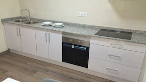A compact kitchen with a built-in dishwasher, a double sink, and a countertop with a toaster. - Europa House Village (San Vicente del Raspeig)