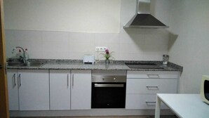 A compact kitchen with white cabinets, a stainless steel dishwasher, a toaster, and a microwave. - Europa House Village (San Vicente del Raspeig)