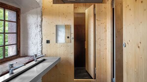 A bathroom with wooden walls, a window, a mirror, and a shower area. - Youth Hostel Mariastein (Metzerlen)