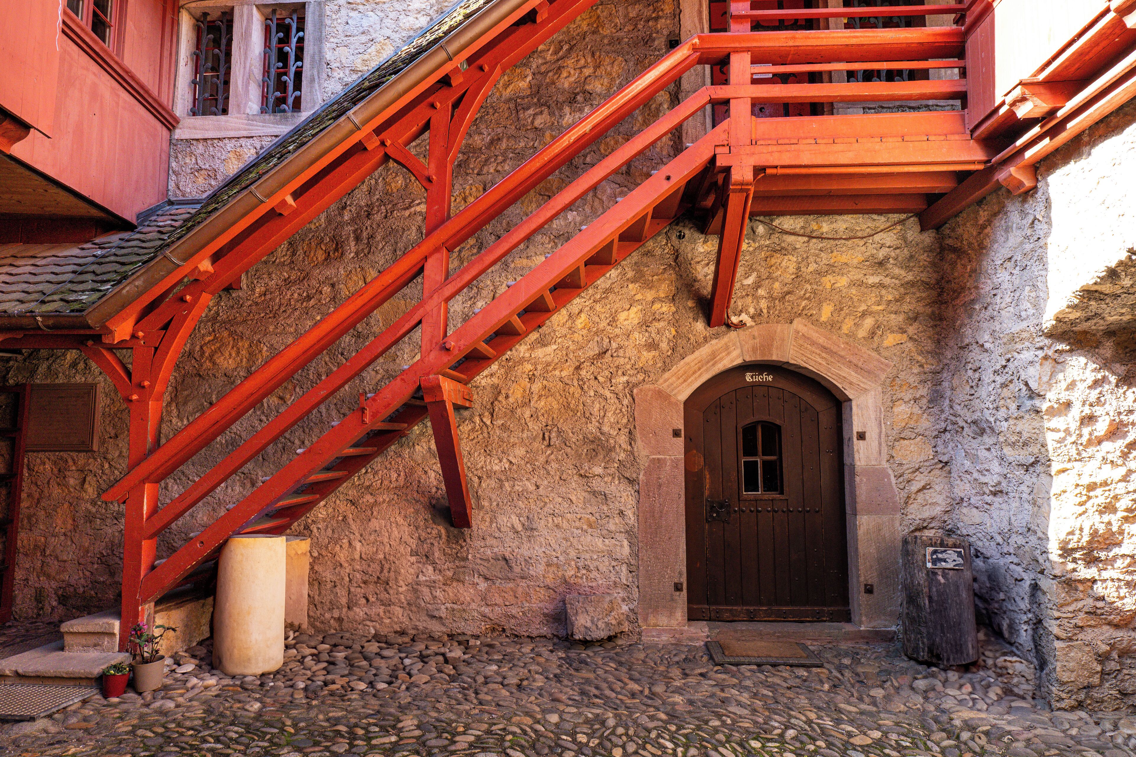 A stone building with a wooden staircase leading to a door.