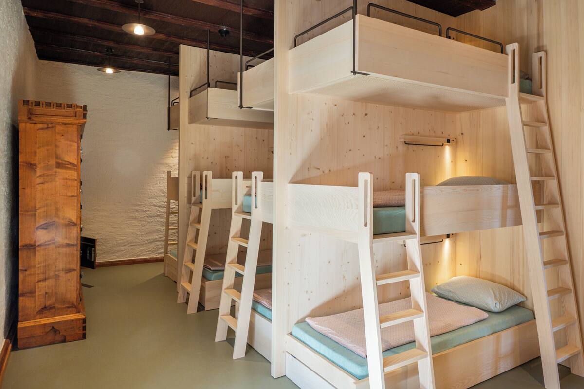 Des lits superposés avec des échelles en bois, une armoire en bois et un mur à texture.