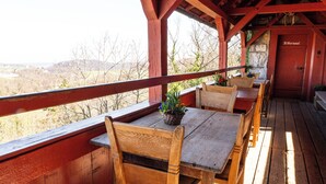 A wooden deck with a table and chairs, overlooking a scenic landscape. - Youth Hostel Mariastein (Metzerlen)