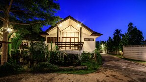 A two-story house with a porch, surrounded by lush greenery. - Baan Suan Nuanta (Samut Songkhram)
