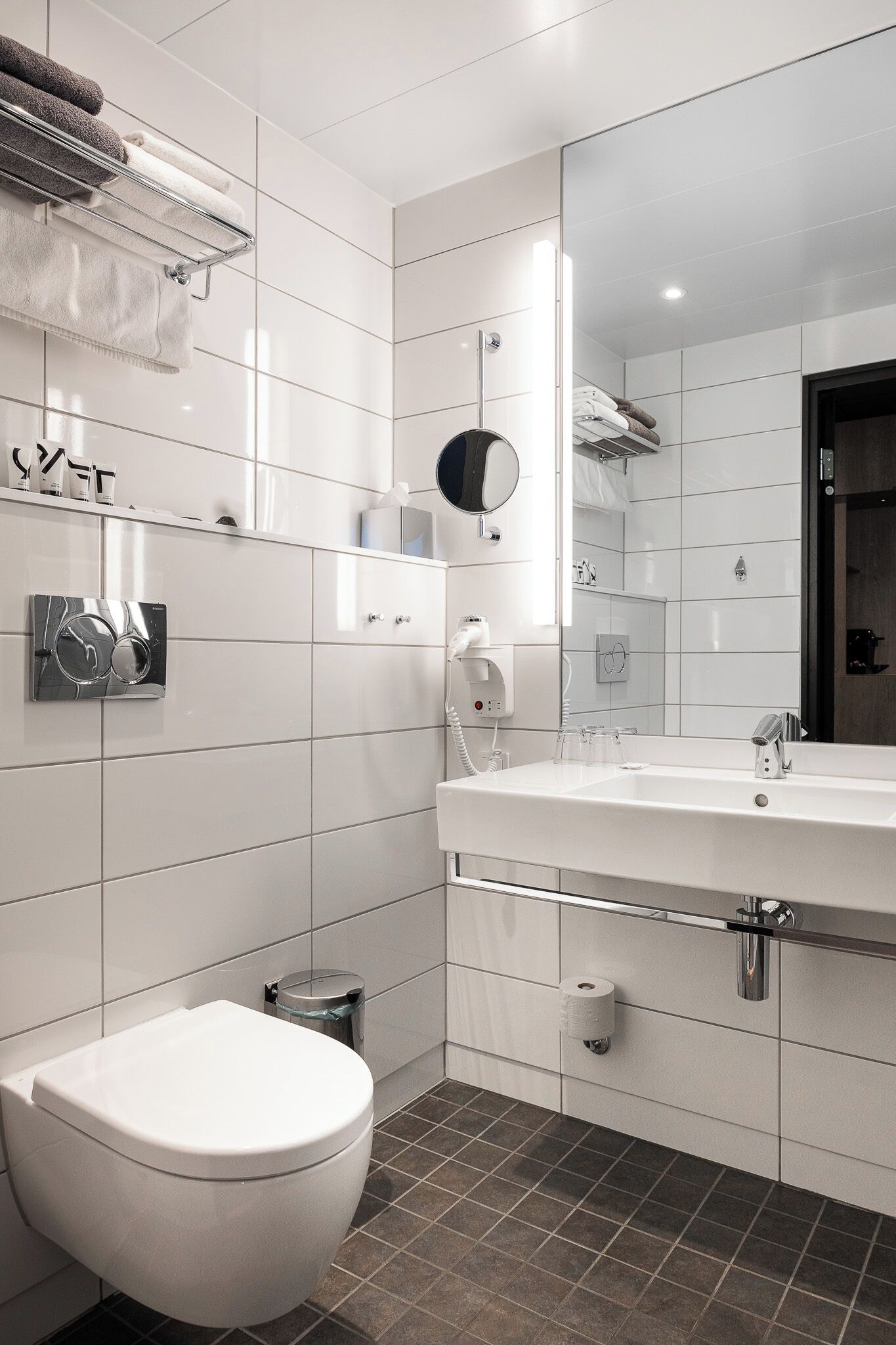 Een moderne badkamer met een wit toilet, een wastafel met spiegel en een handdoekrek.
