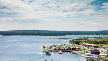A lakeside RV park with multiple cabins and boats, surrounded by forested hills and a clear sky.