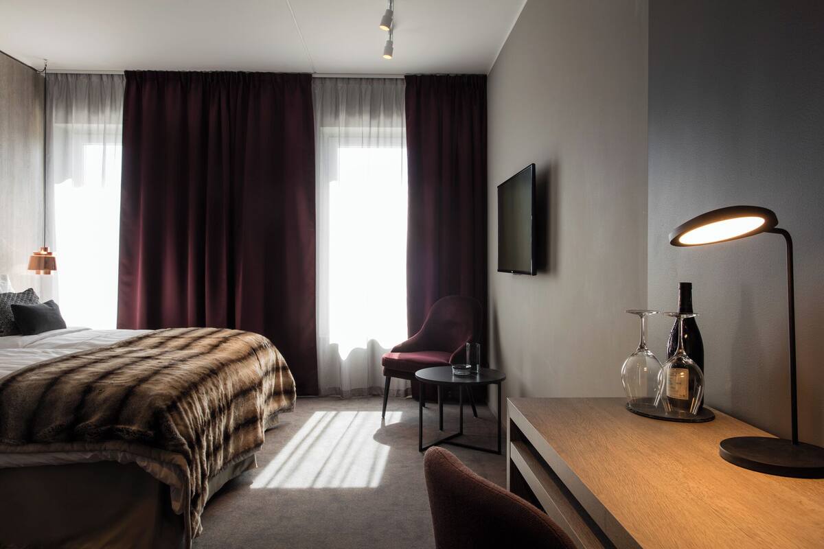 Een hotelkamer met een bed, een bureau, een stoel, een televisie en een lamp.