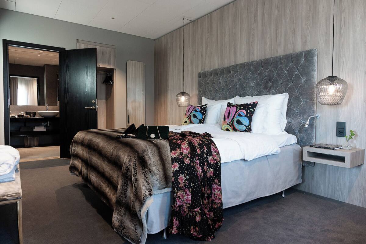 Een moderne slaapkamer met een groot bed, een nachtkastje, een spiegel en een kledingkast.