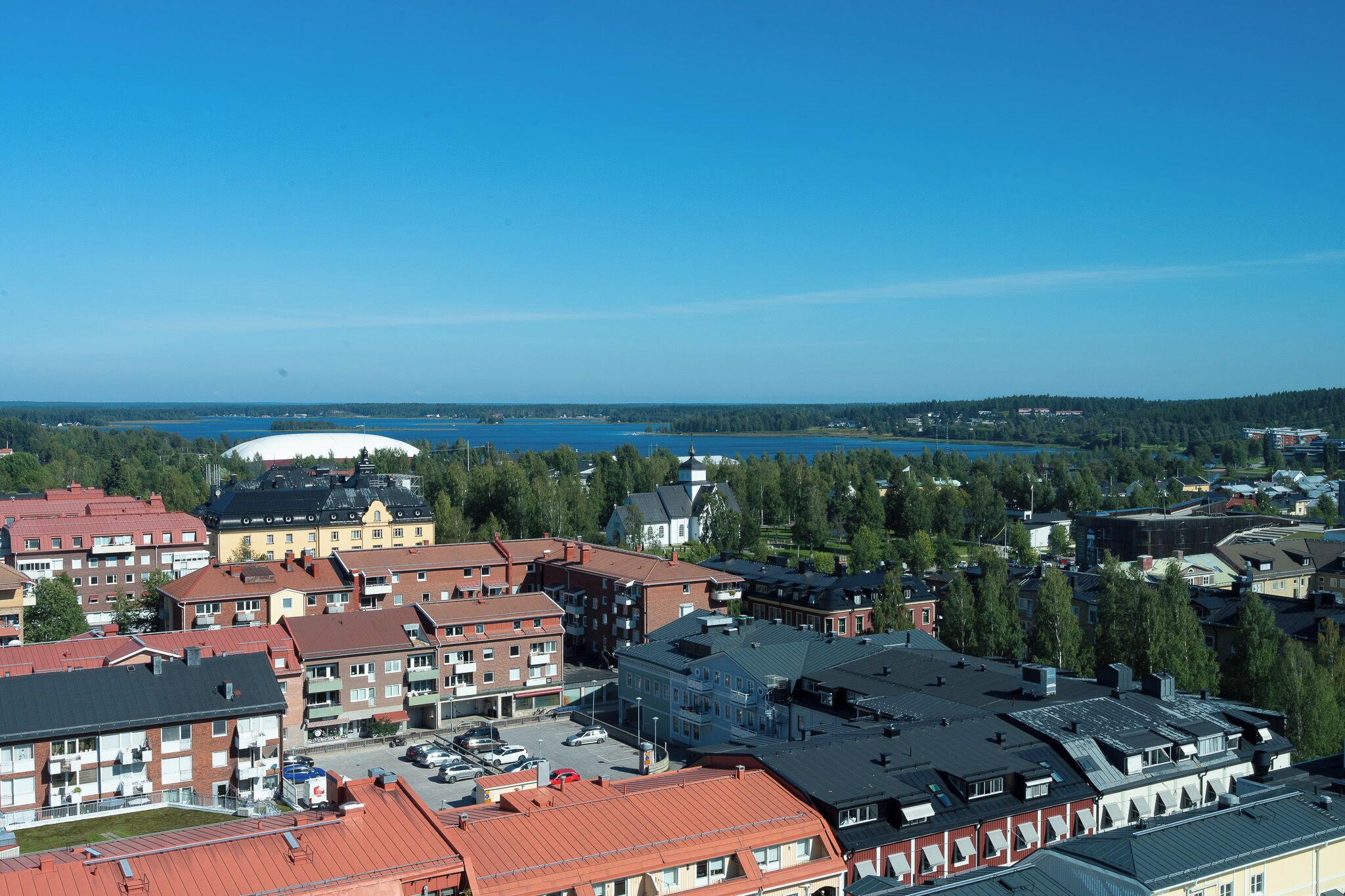 A residential area with multiple apartment buildings, a large stadium, and a lake in the background.